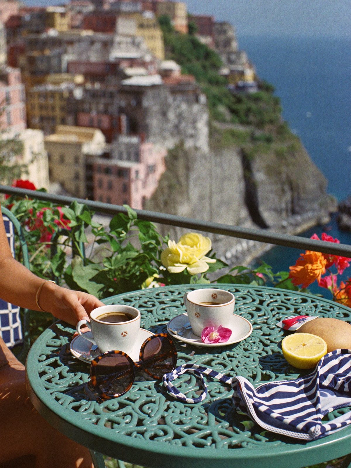 Espresso, lemons and a folded striped swimsuit on a cafe table above the sea