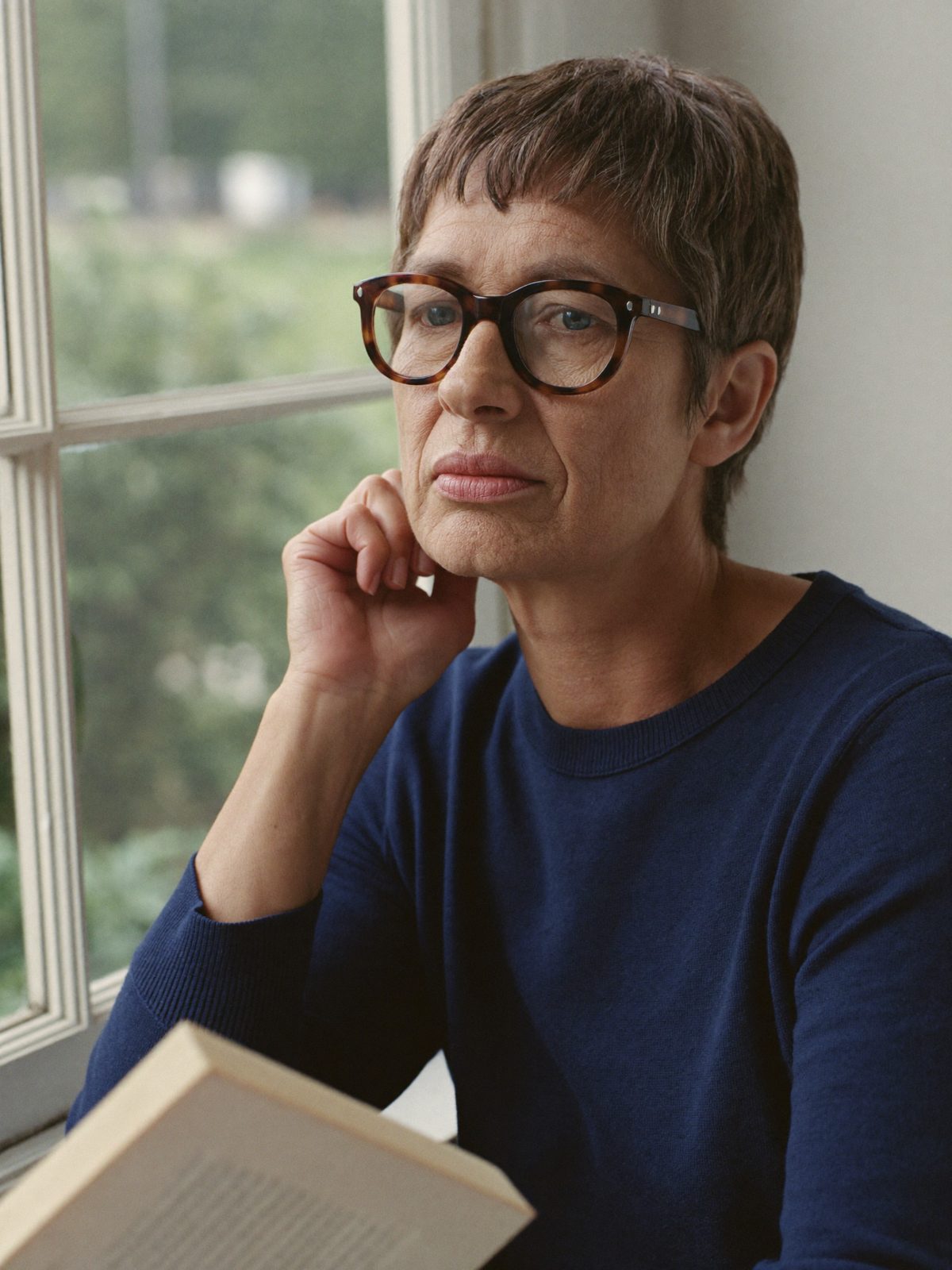 Philippa Ashdown, novelist, by a window with a book