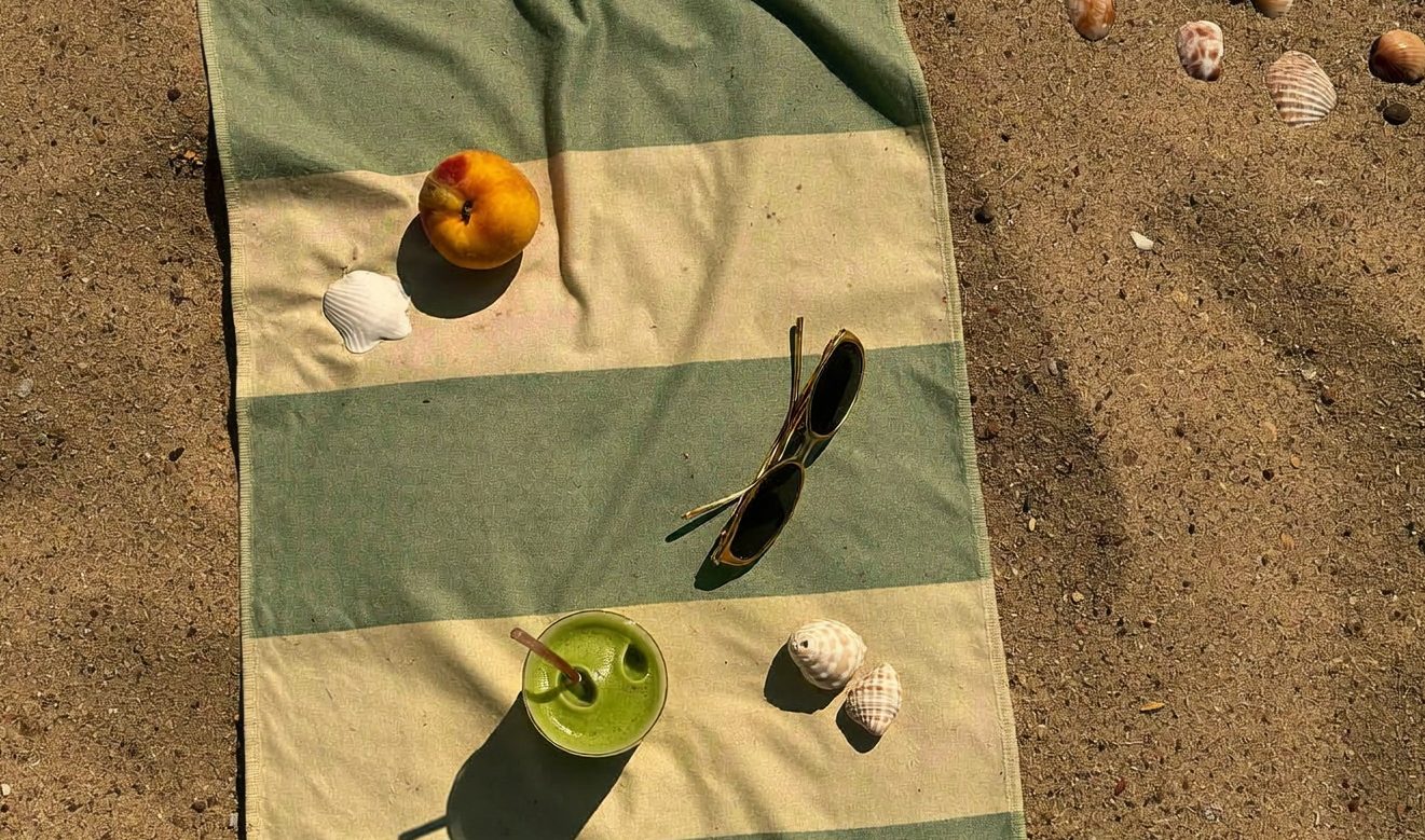 Golden Hour towel in sage stripe on the sand